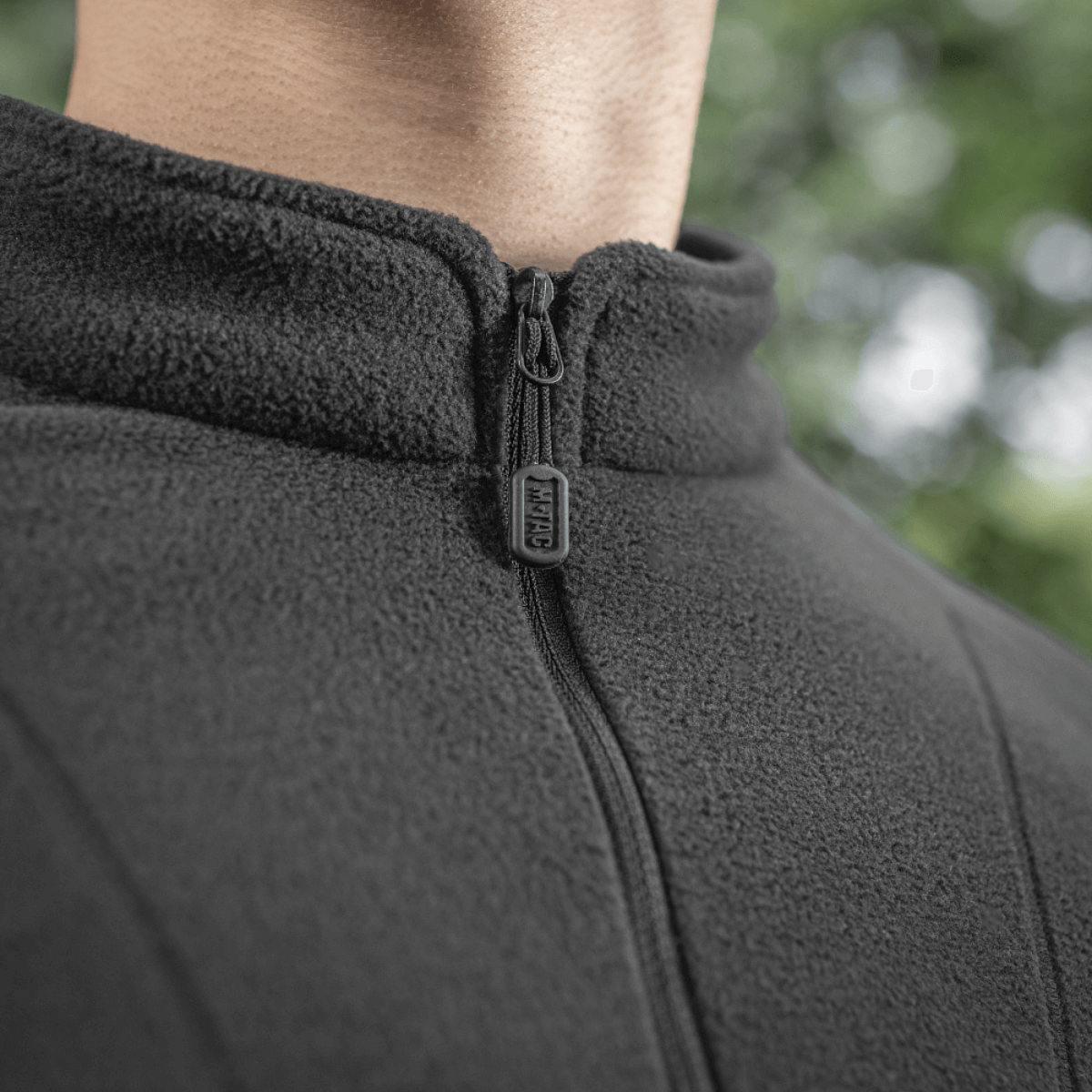 Nærbillede af M-Tac Delta Polartec Raglan Jakke i sort fleece med lynlås og høj krave, ideel til udendørs brug og beskyttelse mod kulde.