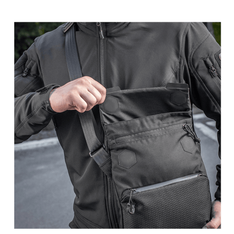 Mies kantaa M-Tac Konvert Taske Eliteä Cordura 500D:llä, näyttää magnetventilin nopeaa käyttöä varten, säädettävä olkahihna.