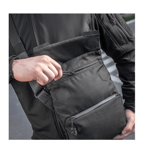 Mies kantaa M-Tac Konvert Taske Eliteä, valmistettu kestävästä Cordura-materiaalista, magnetlukning ja säädettävä olkahihna.