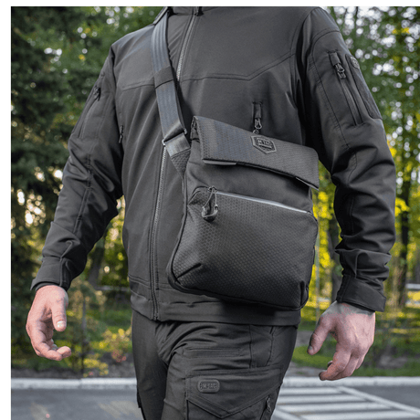 Mies kantaa M-Tac Konvert Taske Eliteä Cordura-materiaalista, säädettävä olkahihna ja tablet-design, ulkokuvassa.