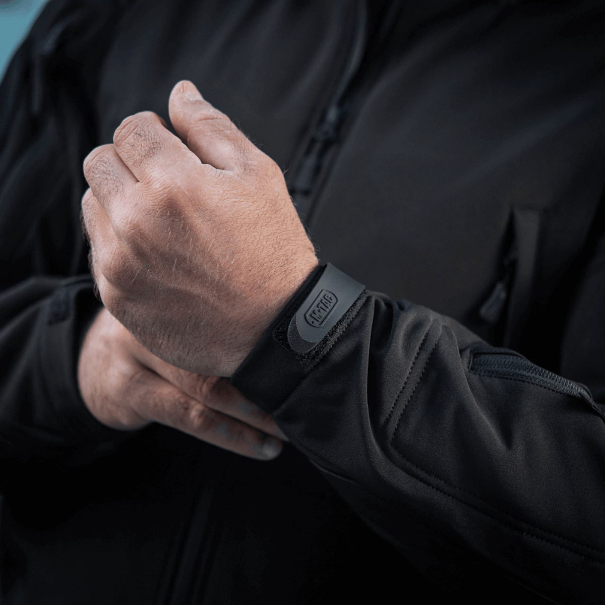 Mand justerer manchet på M-Tac Soft Shell Jakke, viser letvægtsdesign og vejrbeskyttende materiale.