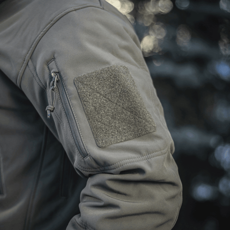 M-Tac Soft Shell Jakke med Liner med aftagelig foer og lomme detalje vises i et naturligt miljø.