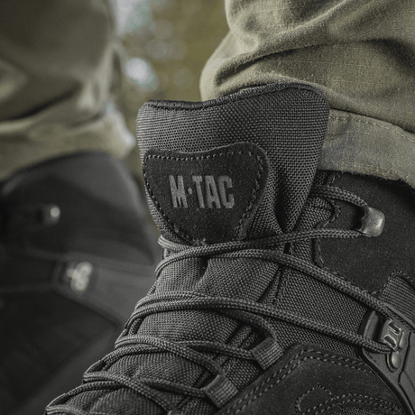 M-Tac Taktiske Sæsonstøvler mustasta nahasta ulkokäyttöön, lähikuva nauhoista ja logosta.