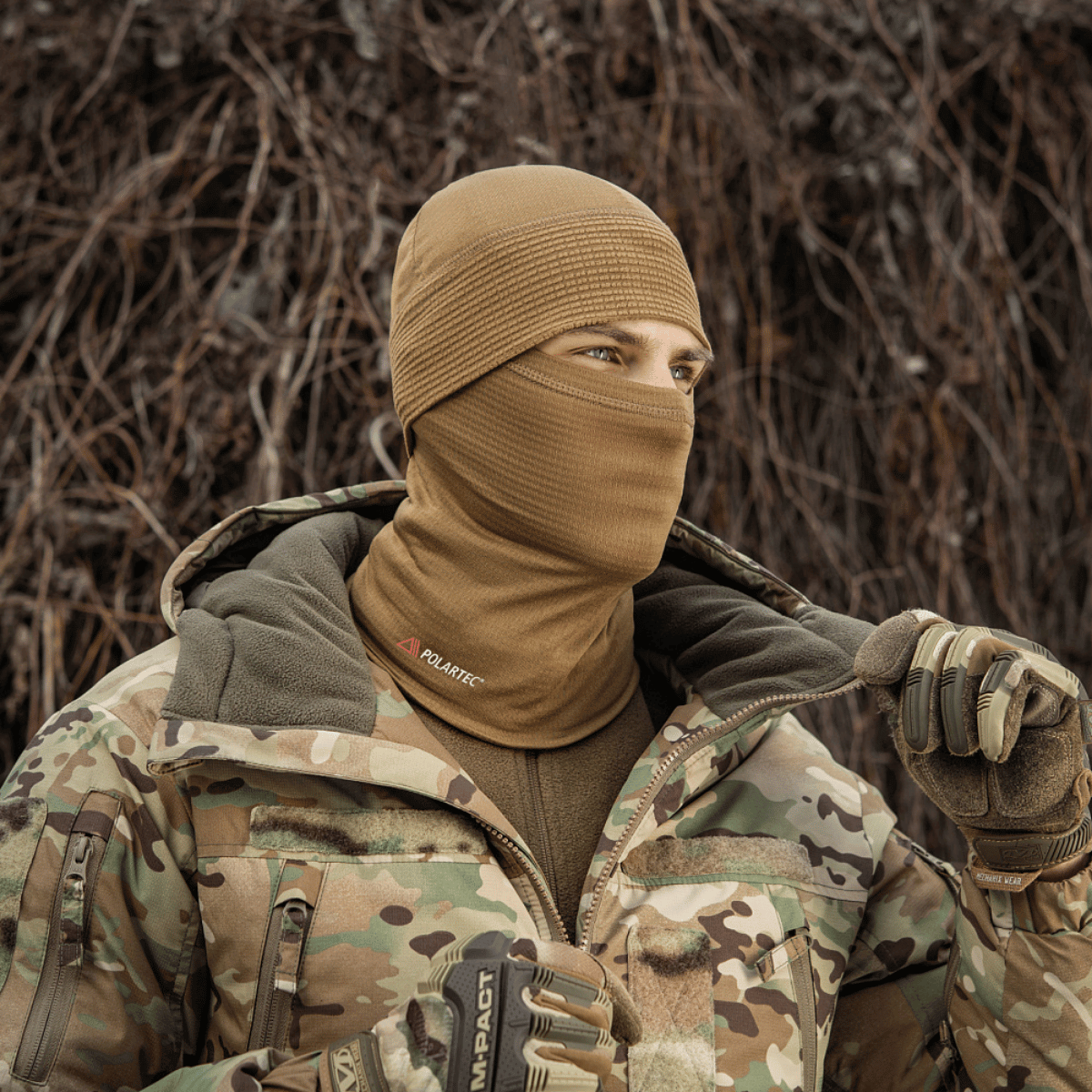 Person iklædt M-Tac Tube Scarf Polartec Power Grid i en camouflagedragt, der beskytter mod kulde, vind og tjener som ansigtsmaske.