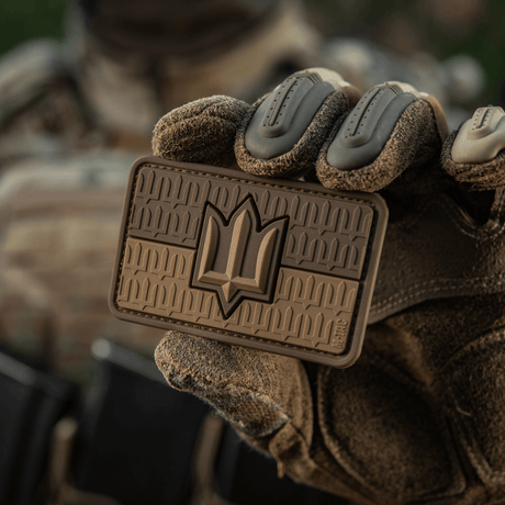Henkilö pitelee M-Tac-patchia Ukraine Flag ZSU Trident PVC, joka ilmaisee Ukrainan armeijan ylpeyden ja kansallista perintöä 3D-muotoilussa (3d en).