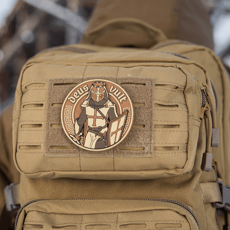 M-Tac Deus Vult 3D PVC patch kiinnitetty reppuun Velcrolla, näyttää 3D-muotoilun ja tekstin 'Deus Vult', sopii sotilaskäyttöön ja airsoftiin.