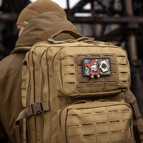 Taktinen reppu, jossa M-Tac Patch Joker Skull 3D PVC jokeri- ja kuolemakorttikuviolla PVC:stä kiinnitettynä repun etuosaan.