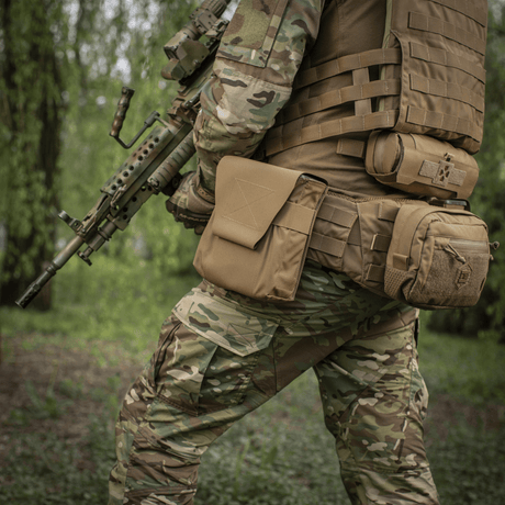 Sotilas, jolla M-Tac Pouch til M249 Cartridge Box Closed kiinnitettynä taktiseen liiviin kenttäympäristössä, korostaa kestävyyttä ja toimivuutta (m249).