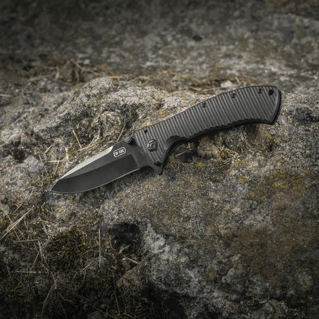 M-Tac Outdoor & Militær Type 7 mustassa pinnoitteessa kalliotaustalla.