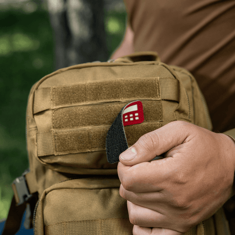M-Tac Patch Flag 25x80 Mini Squares laukussa, pidetään kädessä. Cordura 500d, velcro-kiinnitys, laserleikkaus, kulutusta kestävä ja kevyt patch