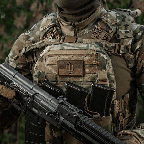 Sotilas maastoliivissä, jossa M-Tac-tarra Ukraine Flag ZSU Trident PVC, pitää asetta, symboloi Ukrainan ylpeyttä ja perintöä