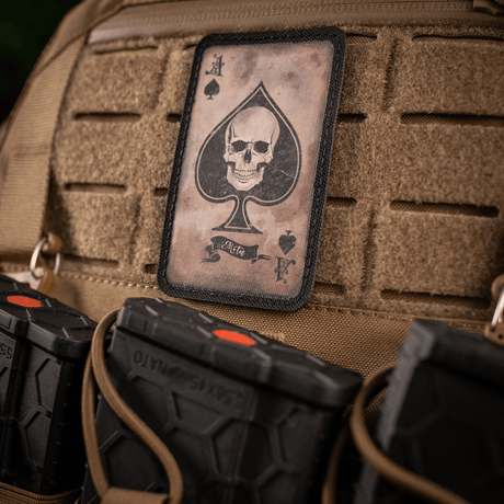 M-Tac Patch Ace of Spades kalloaihe laukussa, symboloi taistelutahtoa ja tyyliä. Cordura 500D, Velcro-kiinnitys.