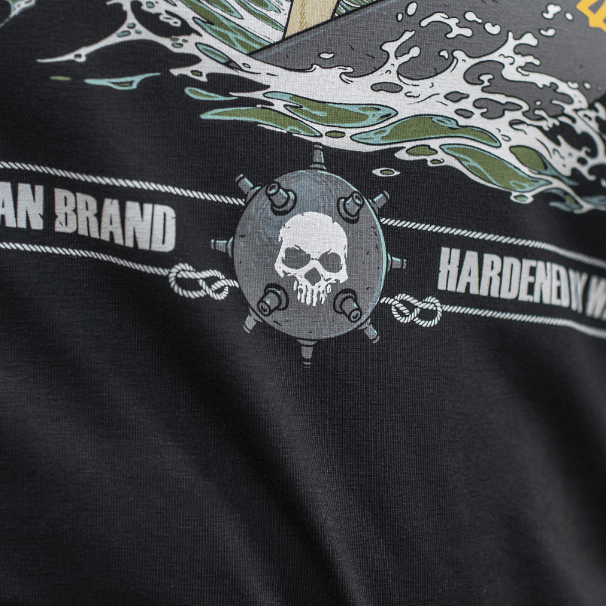 Close-up af M-Tac T-Shirt Surf Club med grafik af dødningehoved, bølger og tekst, inspireret af specialoperationer og surfscener.