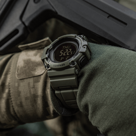 M-Tac Tactical Ur med Kompas 2233 sotilasvarusteisessa käsivarressa, tutkimus- ja ulkoiluseikkailuihin, kestävä kello kompassilla ja LED-näytöllä.