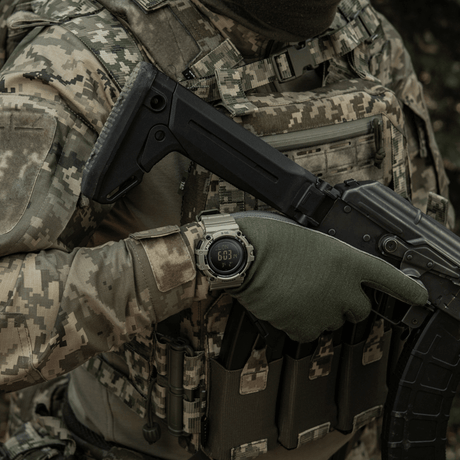 Henkilö maastopuvussa kantaa M-Tac Tactical Ur Kompas 2233 sotilasympäristössä en
