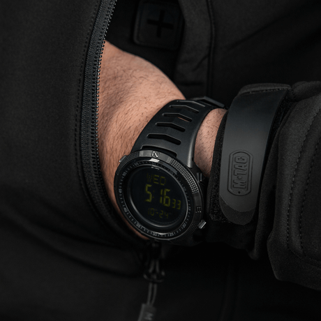 M-Tac Tactical Ur 2147 kädessä, näyttää tukevan muotoilun, kestävyyden ja ulkotoiminnot kuten kompassin ja LED-taustavalon.