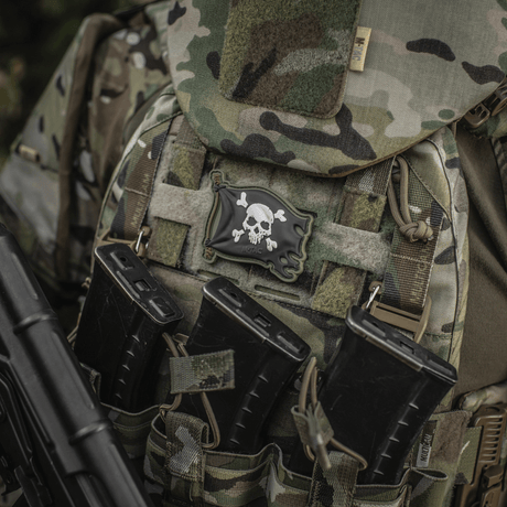 M-Tac Patch Jolly Roger PVC kiinnitettynä taktiseen reppuun maastokuvioinnilla, symboloi seikkailunhalua ja päättäväisyyttä.