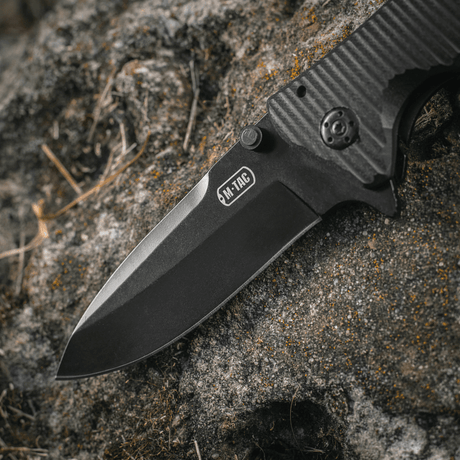 M-Tac Outdoor & Militær Type 7, mustapinnoitettu ruostumattomasta teräksestä tehty terä kalliopinnalla.