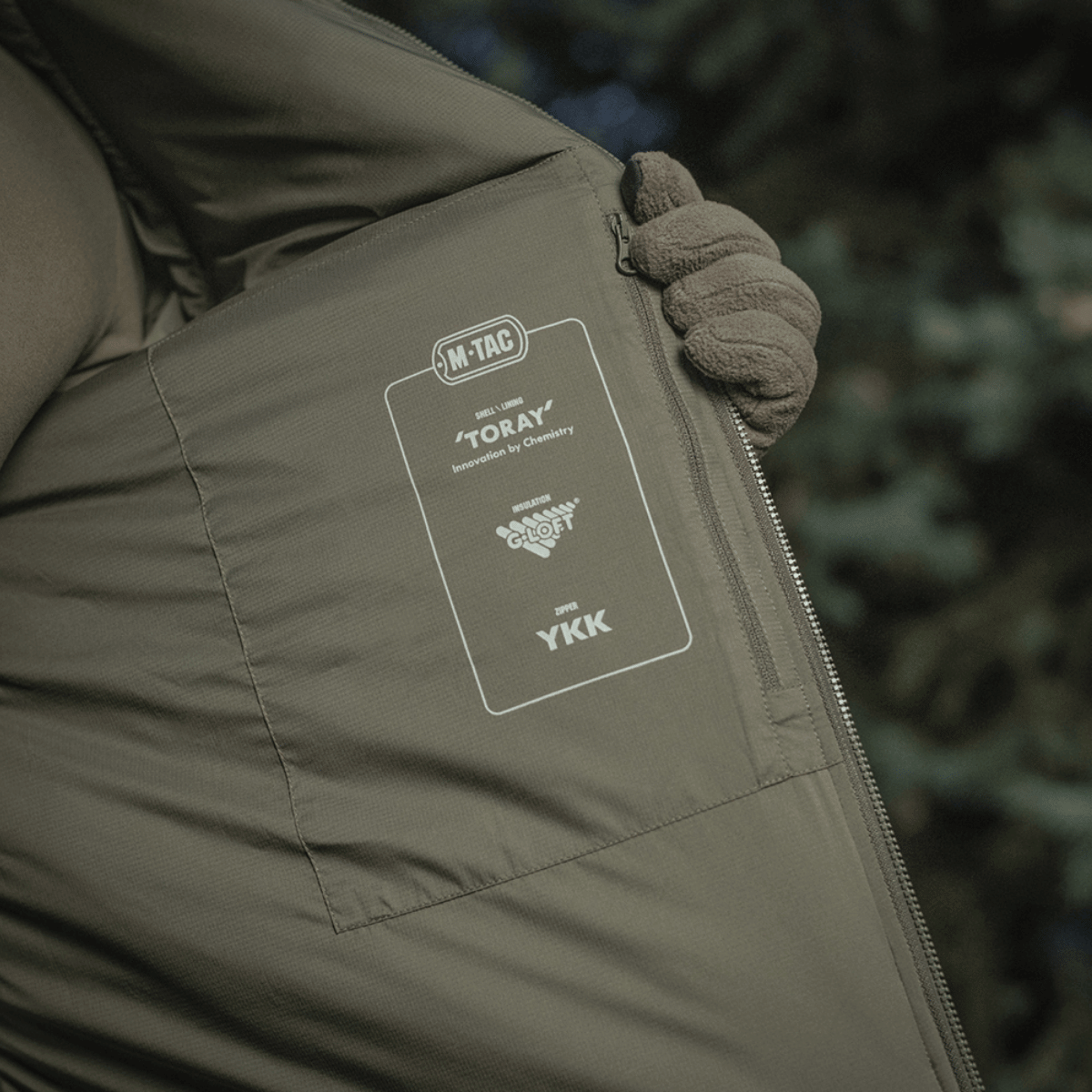 M-Tac Paladin Jakke med detaljeret indvendig etikette fra Toray og YKK lynlås, fremhæver jakkenes kvalitetsmaterialer.