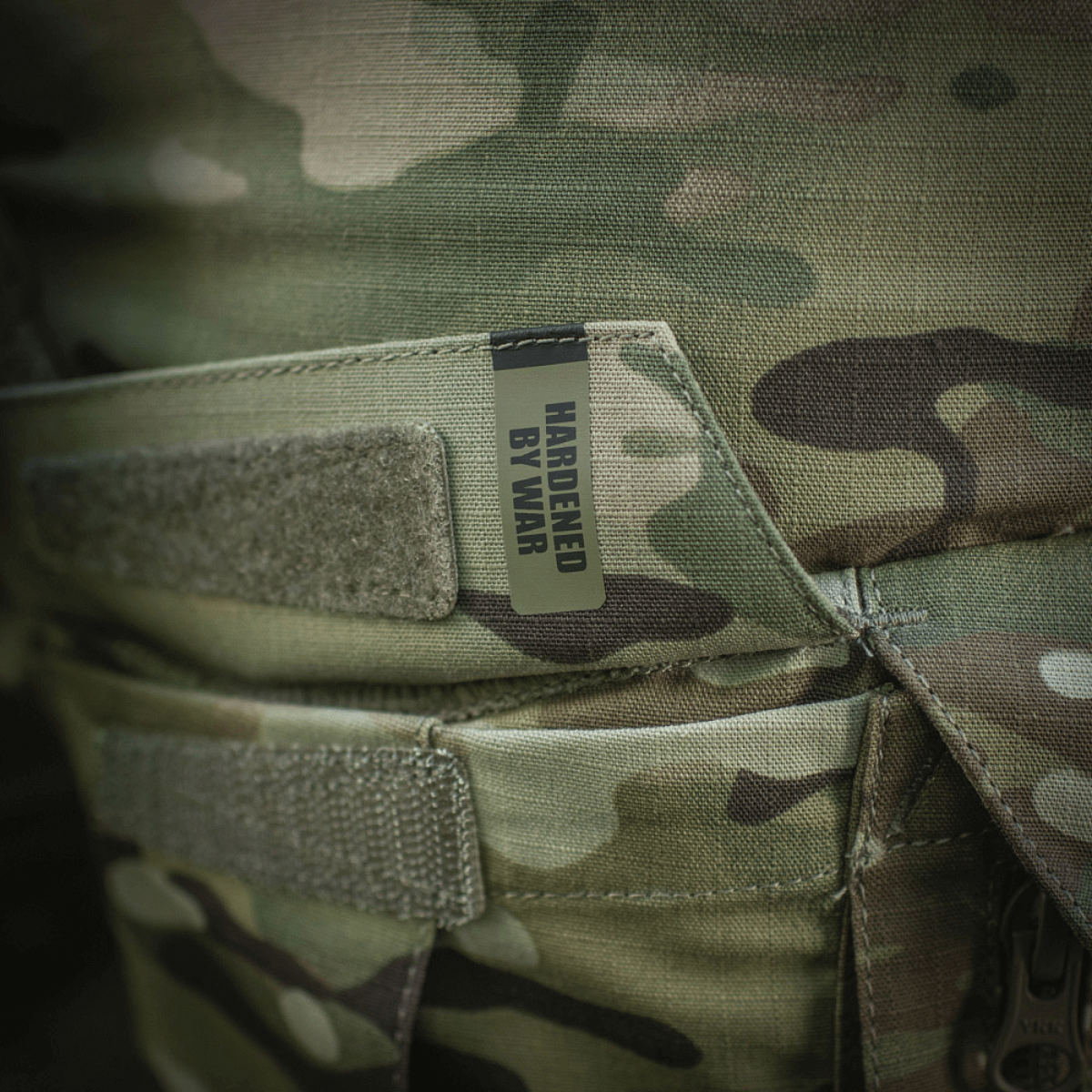 Detaljer af M-Tac Shorts STURM Gen.II Nyco Extreme med camouflagemønster og "Hardened by War" etiket, ideel til taktisk brug.