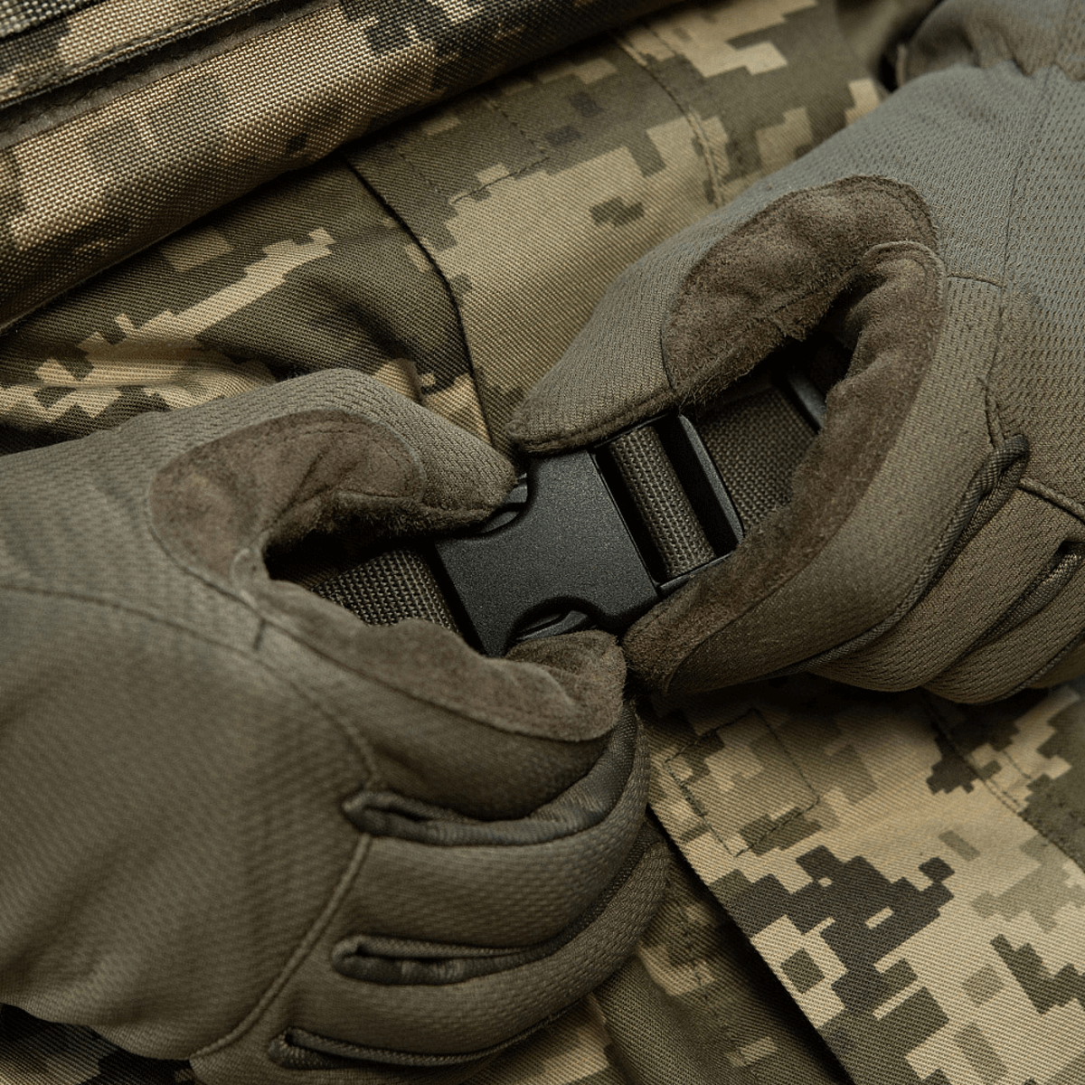 Nærbillede af hænder med M-Tac Siddeunderlag med bælte i kamuflage mønster