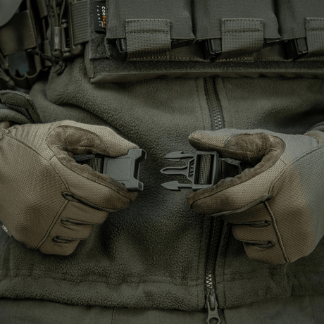Præsentation af M-Tac Siddeunderlag med bælte brugt i taktisk miljø med handsker, klar til kold vejr udendørs aktiviteter.