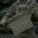 M-Tac Siddeunderlag med bælte i brug udendørs i skovomgivelser, praktisk og robust design til udendørs eventyr