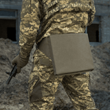 M-Tac Siddeunderlag med bælte i brug af soldat i camouflageuniform, set bagfra på en jordet undergrund.