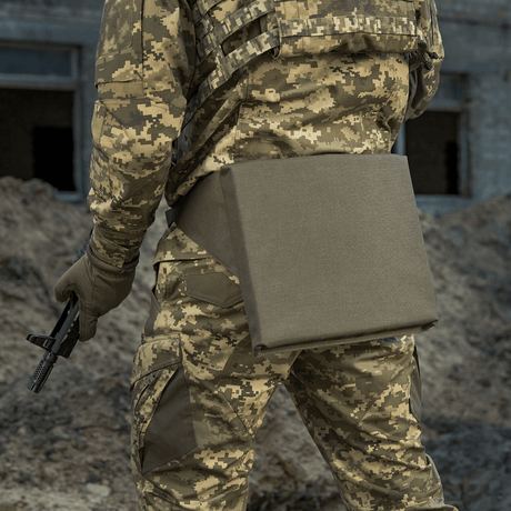 M-Tac Siddeunderlag med bælte i brug af soldat i camouflageuniform, set bagfra på en jordet undergrund.