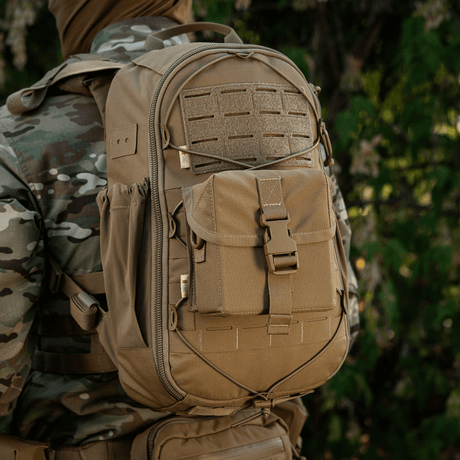 M-Tac Taske til Natkikkert PVS-14 bæres af en person i camouflagejakke. Tasken har praktiske rum og sikker fastex-lukning.