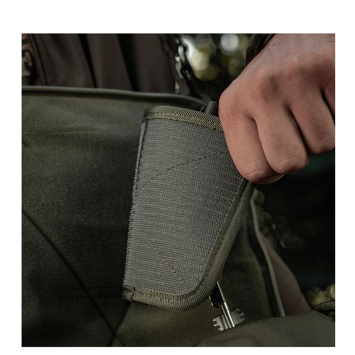 Person fastgør M-Tac Hook & Loop Low Profile Admin Panel i en taske, modulært organiseringssystem.