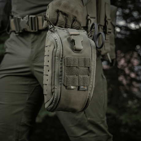 M-Tac Medical Pouch Elite Rip Off i brug til taktisk førstehjælp i felten, med hurtig adgang via træk i håndtaget.