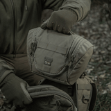 Person holder M-Tac Toilettaske Elite Gen.II designet til rejser og opbevaring af hygiejneartikler i naturen.