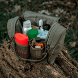 M-Tac Toilettaske Elite Gen.II fyldt med hygiejneartikler på en træstamme udendørs
