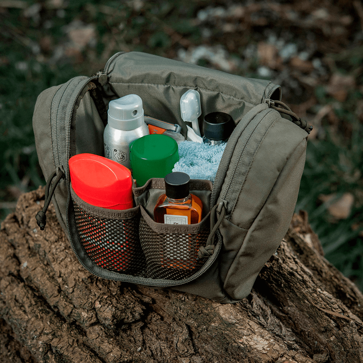 M-Tac Toilettaske Elite Gen.II fyldt med hygiejneartikler på en træstamme udendørs