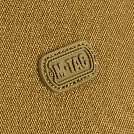 Close-up af M-Tac Toilettaske logo på slidstærkt 600D polyester med PVC-belægning, perfekt til kompakt opbevaring og rejsebrug.