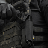 M-Tac Tourniquet Pouch Elastisk VELCRO Gen.II monteret på en taktisk vest med en person der holder en tourniquet.