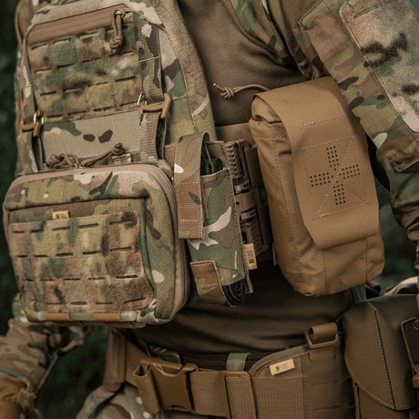 M-Tac Tourniquet Pouch Elastisk VELCRO Gen.II monteret på taktisk vest i skovkamouflage, lavet af robust Cordura 500D, hurtig adgang.