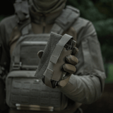 M-Tac Tourniquet Pouch Elastisk VELCRO Gen.II holdes af en taktisk udstyret person for hurtig adgang til tourniquet