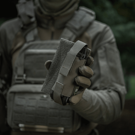 M-Tac Tourniquet Pouch Elastisk VELCRO Gen.II holdes af en taktisk udstyret person for hurtig adgang til tourniquet