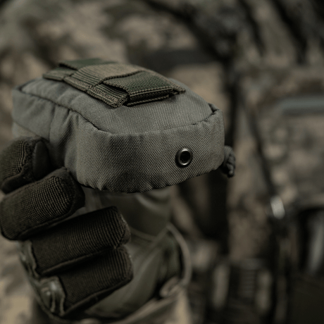 M-Tac PC Utility Pouch Elite i Cordura med MOLLE-interface, holdt af person i taktisk udstyr, ideel til små opbevaringsopgaver.
