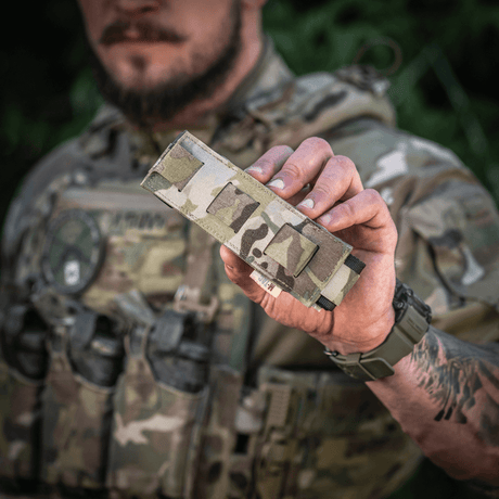 M-Tac Tourniquet Pouch Elastisk med MOLLE Gen.II i camo-design bliver holdt af person med taktisk udstyr, viser let adgang og opbevaring.