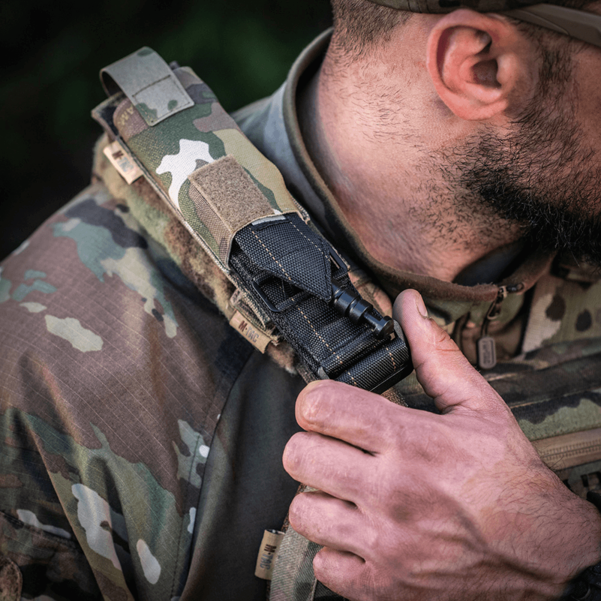 M-Tac Tourniquet Pouch Elastisk med MOLLE Gen.II fastgjort på skulder af en taktisk vest, viser hurtig adgang og holdbarhed.