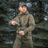 Mand bærer M-Tac Sphaera Hex Hardsling Taske Gen.II Elite i skov, klar til hurtig handling med skjult bæresystem.