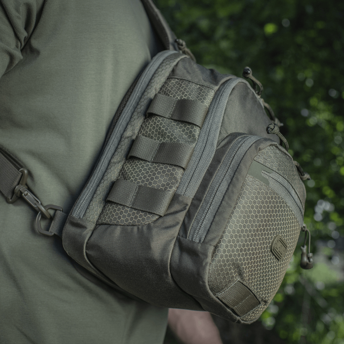 M‑Tac Cross Bag Elite Hex sling pack i Cordura 500, set på skulder i grønne omgivelser, perfekt til daglig brug og taktisk udstyr. 5 liter.
