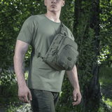 Person iført M‑Tac Cross Bag Elite Hex i skoven, praktisk til daglig brug og taktisk udstyr, lavet af Cordura 500.