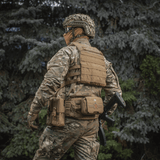 Soldat iført M‑Tac Plate Carrier Cuirass QRS Gen.II i skovmiljø, med quick-release system til taktisk brug. Materiale: Cordura 500D.