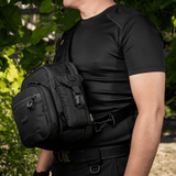 Mand iført sort taktisk udstyr med en M-Tac Smartphone Lomme Elite Large Hex foran, ideel til sikker opbevaring af smartphones op til 6,5 tommer.