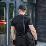 Mand med taske iført M‑Tac Skulderremspude 50 mm Elite ved indgangsdør.