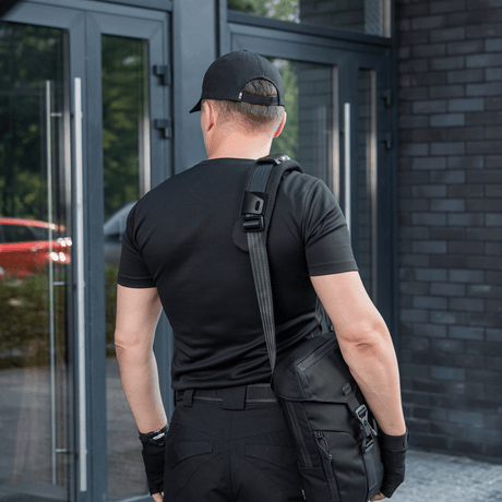 Mand med taske iført M‑Tac Skulderremspude 50 mm Elite ved indgangsdør.